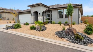 A modern two-story house with a stone facade, a garage, and a landscaped front yard with rocks and small plants. - Pool View at Paseos by RedAwning (Washington)