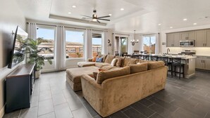 A spacious living room with a large beige sectional sofa, a flat-screen TV, and a ceiling fan. - Pool View at Paseos by RedAwning (Washington)