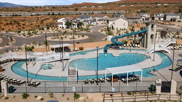 A resort with a swimming pool, a water slide, and a desert landscape in the background. - Pool View at Paseos by RedAwning (Washington)