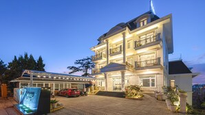 Un hôtel à plusieurs étages doté d’une entrée imposante, d’un espace extérieur couvert et d’un parking.