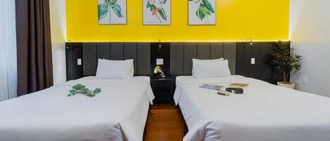 A hotel room with two beds, a nightstand, a lamp, and wall art.
