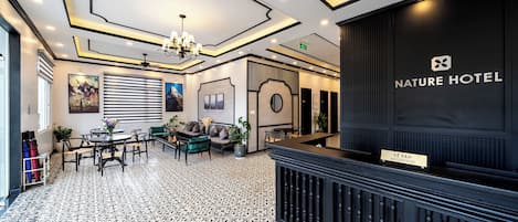 A hotel lobby with a reception desk, seating area, and decorative elements.