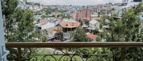 A balcony with a view of a densely packed urban area with various buildings and trees.