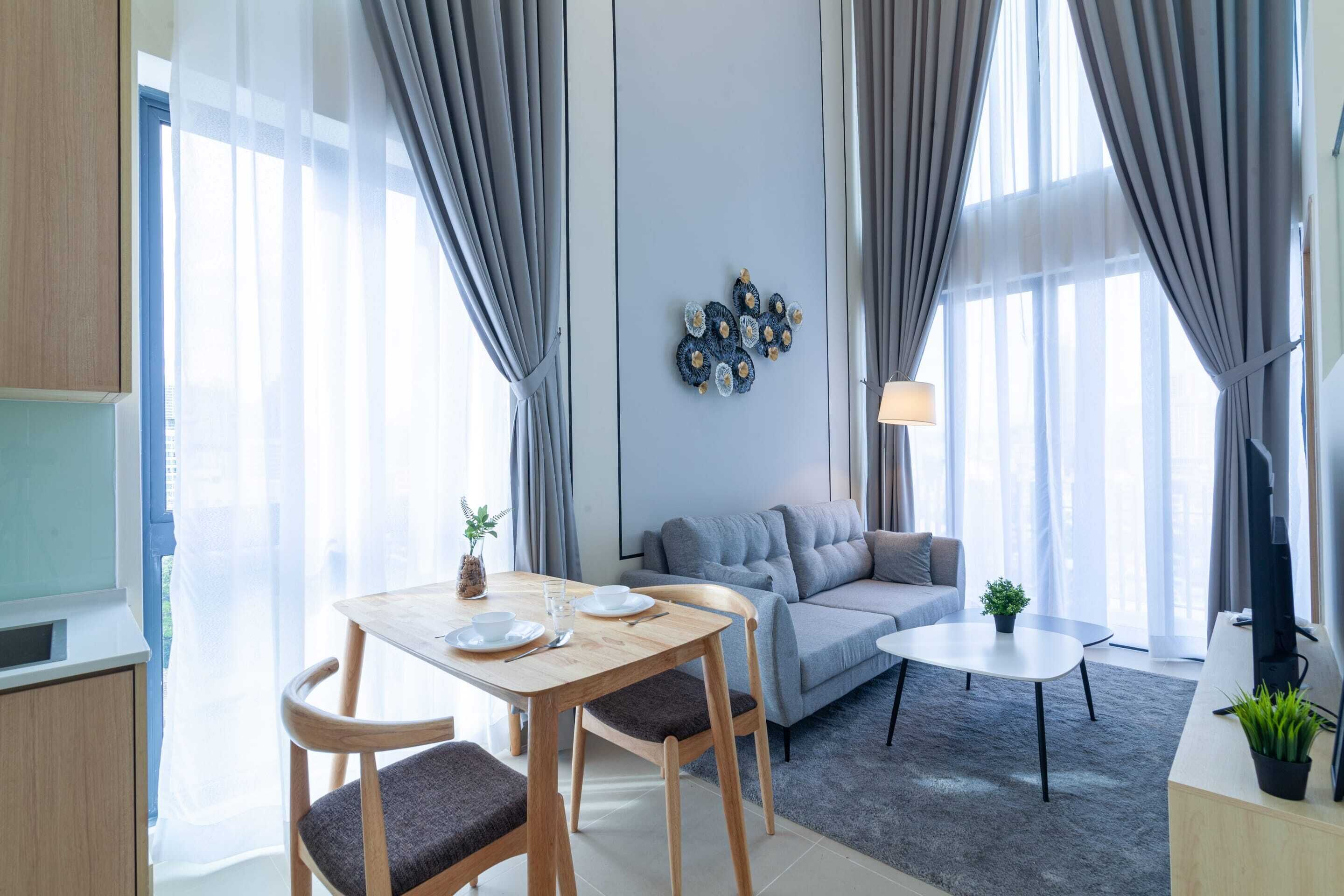 A modern living room with a sofa, a dining table with chairs, and a small coffee table.