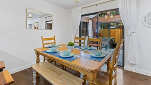A dining area with a wooden table set for four, a bench, and a mirror on the wall.