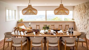 A dining area with a round wooden table, wicker chairs, and two hanging rattan chandeliers. - Miren Estate - lavish hinterland estate with pool (Federal)