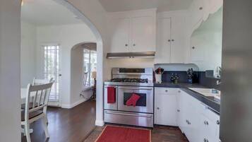 A kitchen with white cabinets, a stainless steel stove, and a red rug.