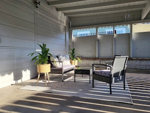 Un espace extérieur aménagé avec des meubles en osier, des plantes en pot et une vue sur un bâtiment en arrière-plan.