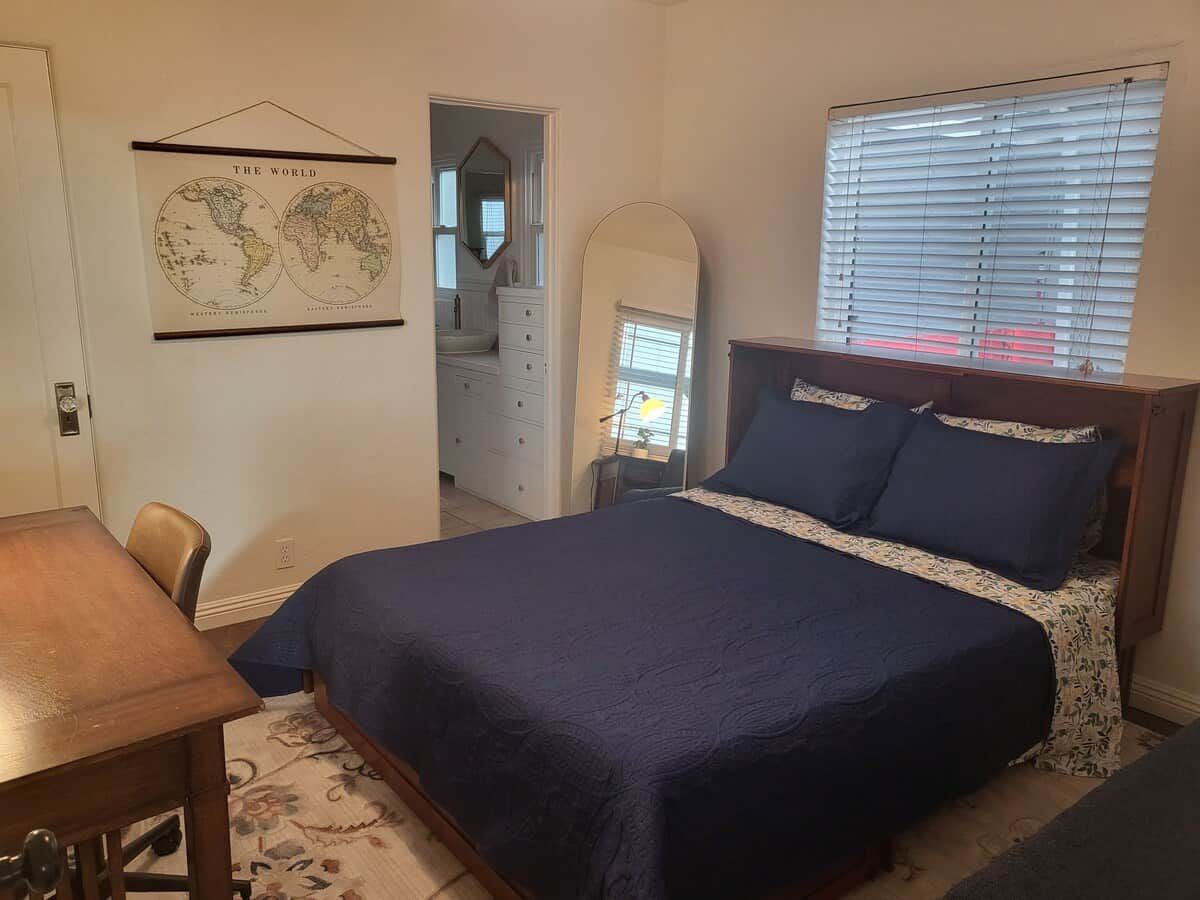 A bedroom with a bed, a dresser, a mirror, and a world map on the wall.