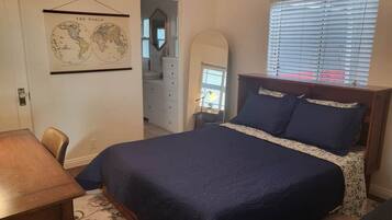A bedroom with a bed, a dresser, a mirror, and a world map on the wall.