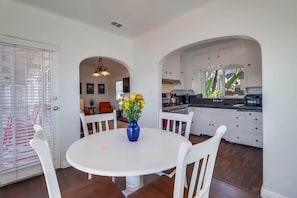Un coin repas avec une table ronde, des chaises blanches et un vase rempli de fleurs jaunes.
