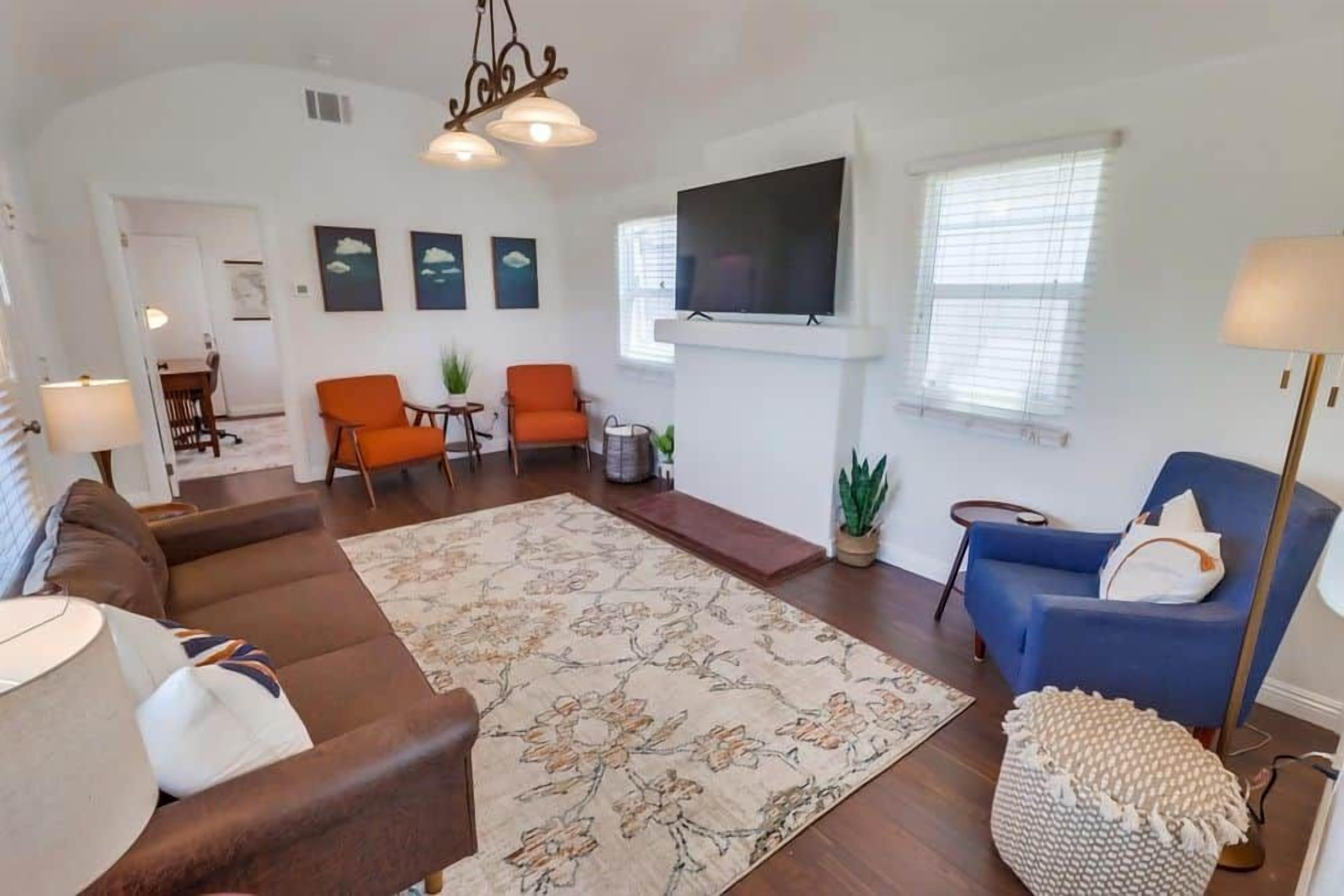 A living room with a sofa, chairs, a TV, and a fireplace.