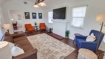 A living room with a sofa, chairs, a TV, and a fireplace.
