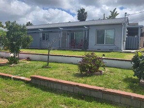 A single-story house with a front porch, a small garden with a brick border, and a clear sky. - Welcoming Bungalow with 2nd BR/Office & Chef's Kitchen (La Mesa)