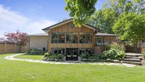 Une maison en bois à deux étages, dotée d’un grand porche à l’avant, d’une façade en briques et d’une pelouse bien entretenue.