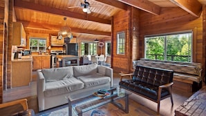 A cozy log cabin interior with a living room, kitchen, and dining area.