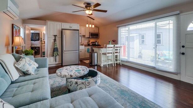 A living room with a sofa, ottoman, and a ceiling fan.