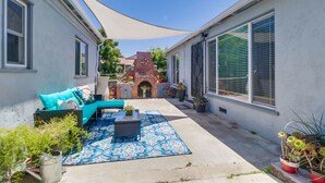A patio area with a blue patterned rug, a black wicker chair, and a turquoise sofa.