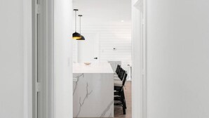 A narrow hallway leading to a kitchen with a white countertop and a marble backsplash. - Delila's Chic 3 Bedroom-2 bath w/ Heated Pool + Game Room (Deerfield Beach)