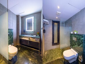 Un bagno moderno con un lavabo in marmo, uno specchio grande, uno spazio doccia in vetro e due servizi igienici.