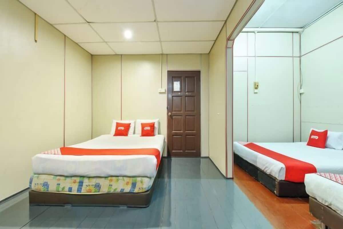 A hotel room with two beds, a wooden floor, and a door leading to another room.