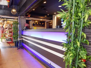Un espace d’accueil au design moderne, doté d’un comptoir à rayures et d’un écran numérique.