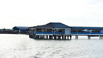 Un muelle frente al agua con varias estructuras de techo azul, probablemente restaurantes o tiendas, que se extiende sobre aguas tranquilas.