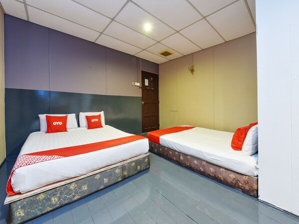 Une chambre d’hôtel avec deux lits, chacun agrémenté de linge de lit blanc et de touches de couleur rouge, un sol à motifs et un plafond doté d’un éclairage encastré.