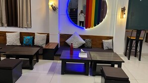 Ein moderner Lounge-Bereich mit einer runden Lichtinstallation, Sitzgelegenheiten und einer Treppe im Hintergrund.