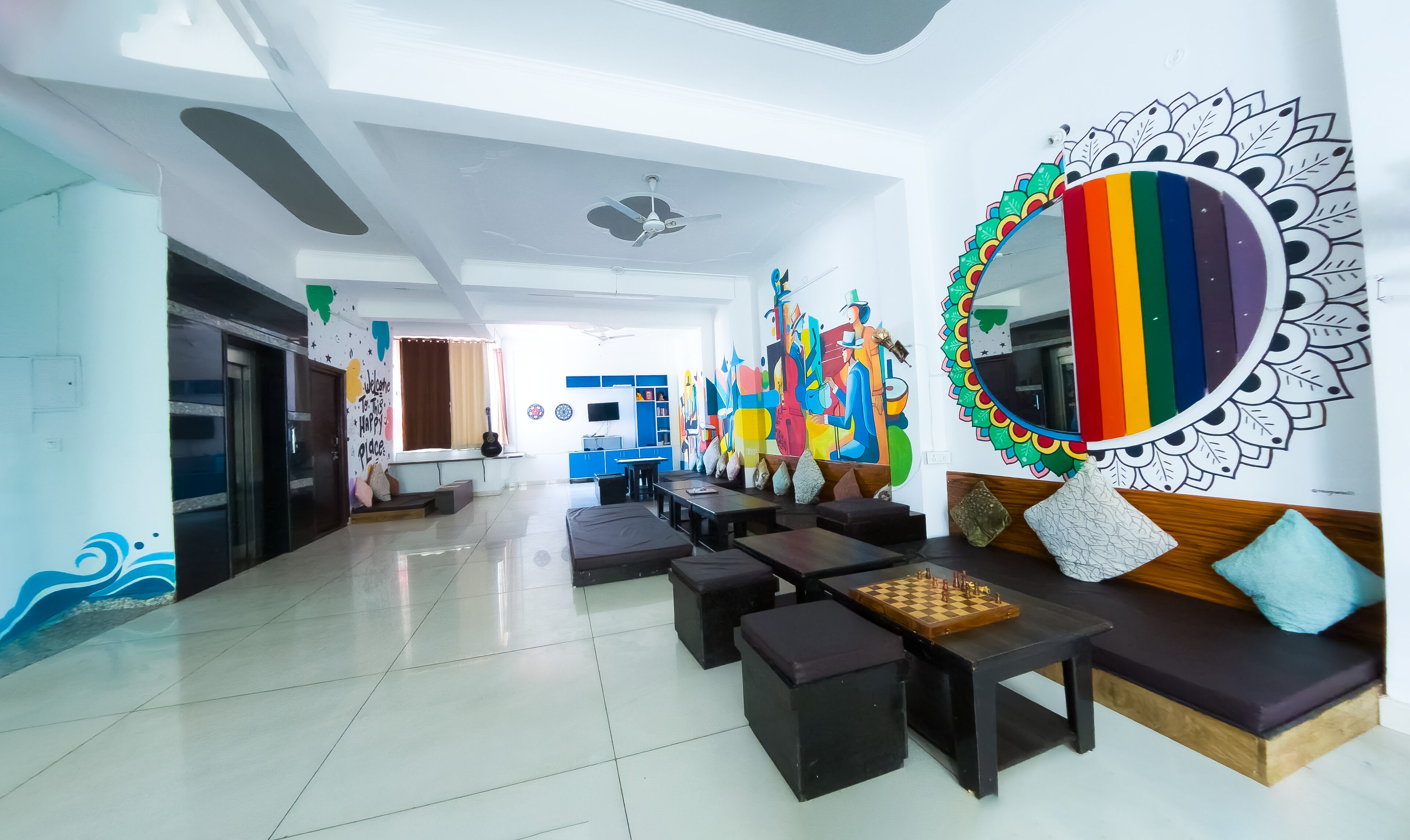 A spacious lobby with a modern design, featuring a large mirror, colorful artwork, and comfortable seating areas.