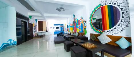 A spacious lobby with a modern design, featuring a large mirror, colorful artwork, and comfortable seating areas.
