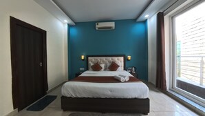 Ein Schlafzimmer mit einem großen Bett, einer dunklen Holztür, einer blauen Akzentwand und einem Fenster mit Vorhängen.
