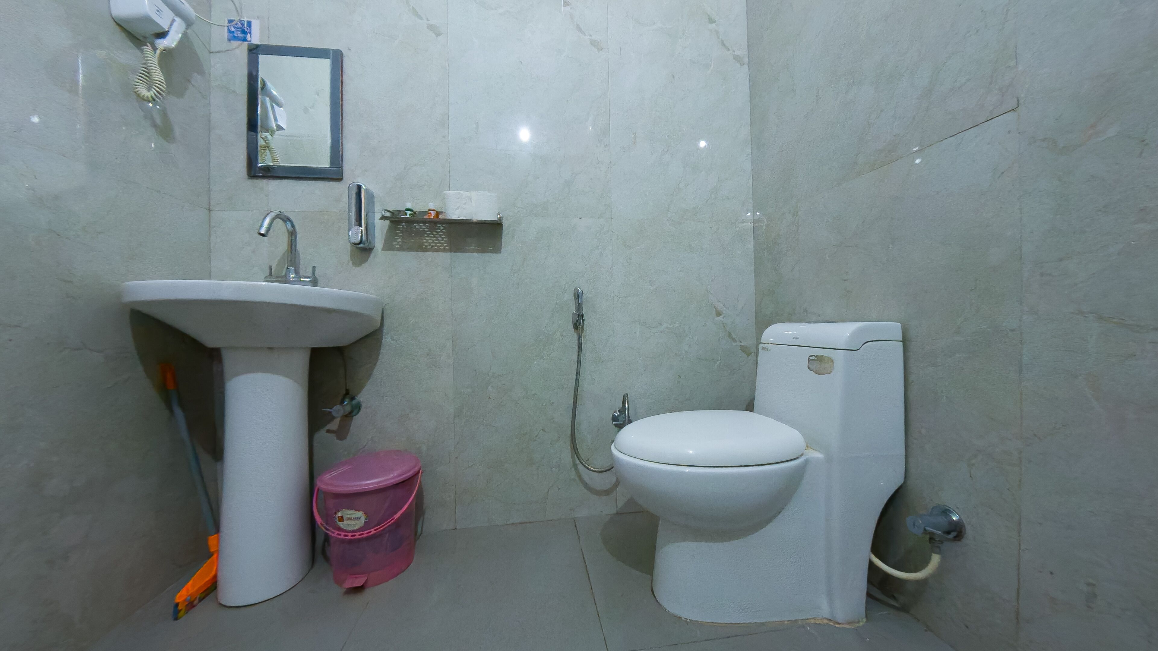 A bathroom with a white sink, a toilet, a shower, and a mirror.