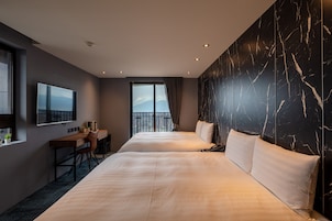 Een hotelkamer met een groot bed, een bureau, een televisie en uitzicht op de bergen.