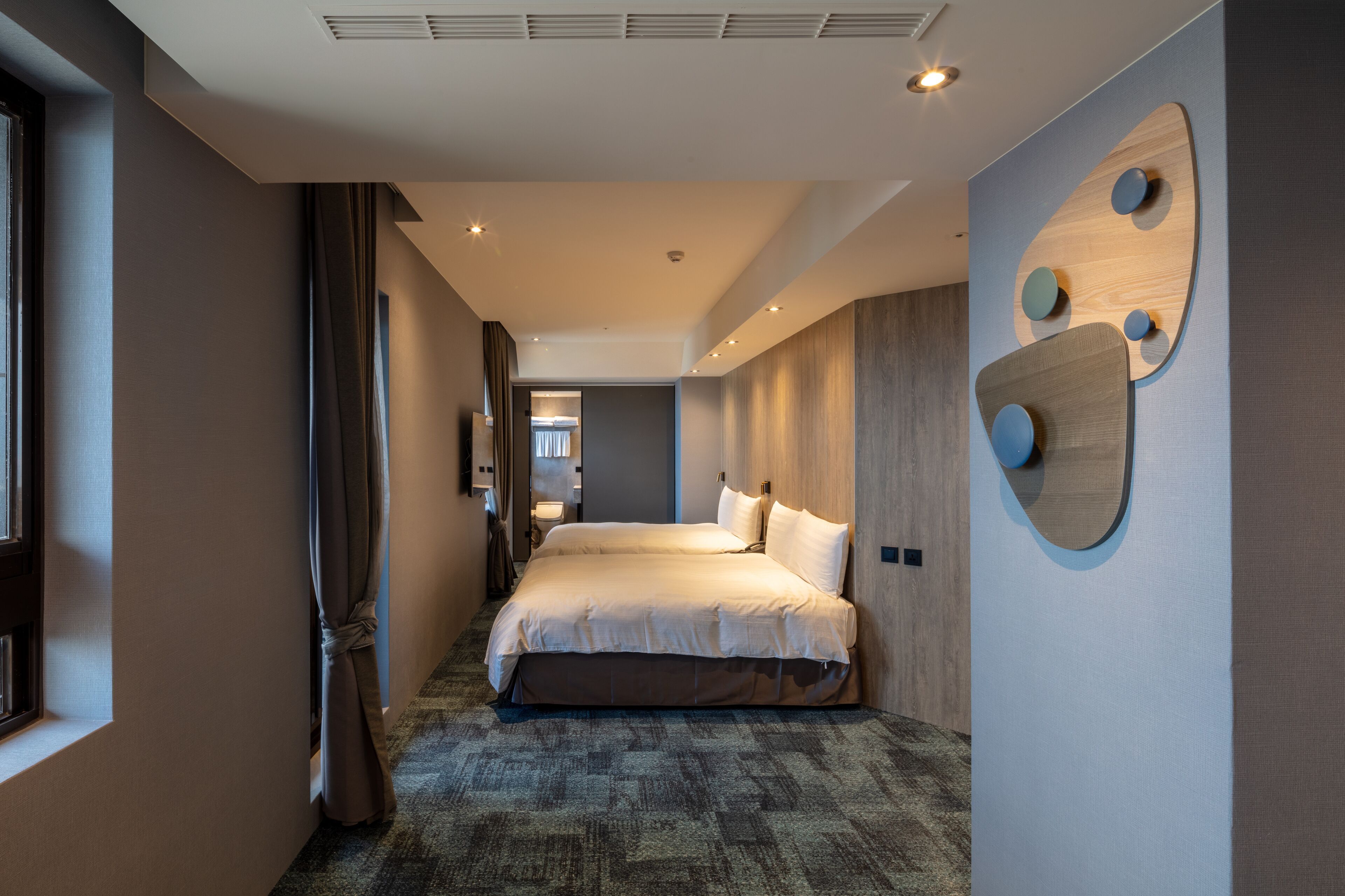 A modern hotel room with a large bed, a wooden accent wall, and a unique wall art piece.
