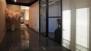A modern hotel lobby with a wooden reception desk, a glass door leading to a seating area, and a large vase of pampas grass. - Roaders Plus Hotel Taipei Station (Taipei)