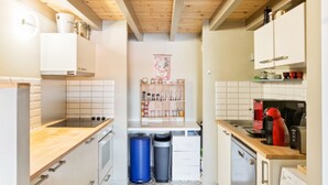 Eine kleine Küche mit Holzbalken, weißen Schränken und einer gefliesten Rückwand.