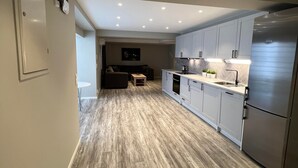 A modern kitchen with a central island, recessed lighting, and a stainless steel refrigerator. - Notodden Sentrum Apartment NO 9 (Notodden)
