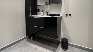 A modern bathroom with a black vanity, a mirror, and a sink. - Notodden Sentrum Apartment NO 9 (Notodden)