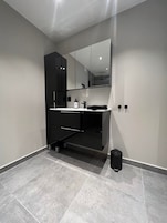 Un baño moderno con un tocador negro, un espejo y un lavabo.