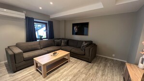A modern living room with a sectional sofa, a wooden coffee table, and a ceiling-mounted air conditioner. - Notodden Sentrum Apartment NO 9 (Notodden)