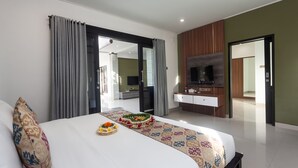 Hotelkamer met een groot bed, een televisie, een bureau en een badkamer zichtbaar door een open deur.