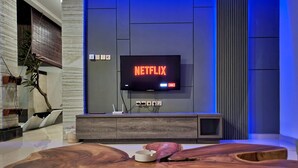 Een moderne woonkamer met een houten salontafel, een flatscreen televisie waarop 'NETFLIX' staat, en een minimalistische dressoir.