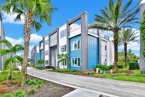 A modern residential building with a central courtyard, surrounded by palm trees and well-maintained landscaping.