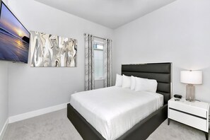 A modern bedroom with a bed, a nightstand, a lamp, and a painting on the wall. - Sleek Two Story Condo near Disney with Resort & Waterpark Access - B27-214 (Kissimmee)