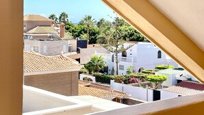 A residential area with terracotta-tiled roofs, white buildings, and lush greenery.