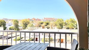A balcony with a view of a cityscape, including buildings and trees.