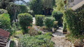 A garden with a stone pathway, a wooden structure, and lush greenery. - Geräumiges Ferienhaus mit Garten (BREUGNON)