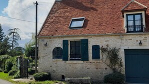 A stone house with a red-tiled roof, a small dormer window, and a garage. - Geräumiges Ferienhaus mit Garten (BREUGNON)
