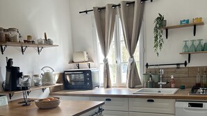 Uma cozinha com bancada de madeira, armários brancos, micro-ondas, cafeteira e pia.